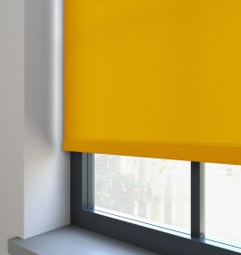 A yellow dimout roller blind in a window