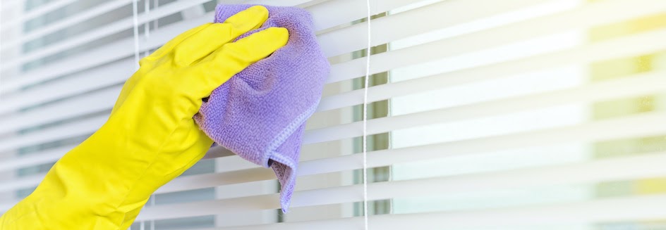 Someone wearing rubber gloves cleans blinds