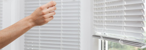 Person pulls cord on white venetian blinds